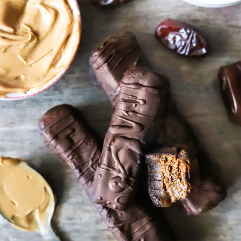 Snickers bars piled on each other, with peanut butter and dates around the edges