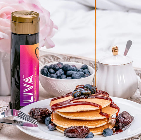 A bottle of liva date syrup behind a blueberry